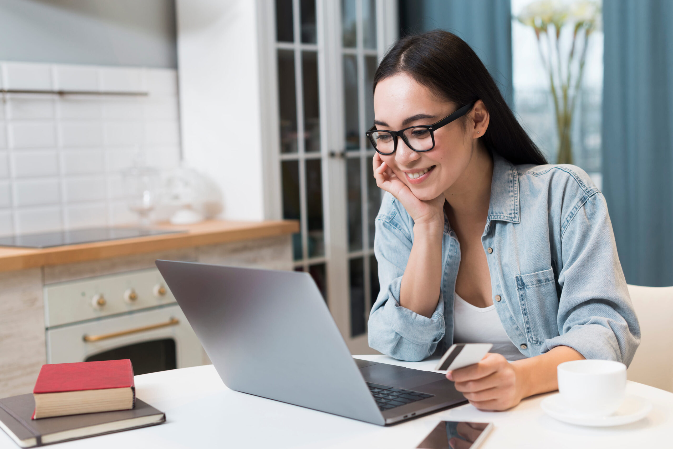 Patient wearing eyeglasses using a laptop to schedule an eye exam online with Foothills Optometry by Granite Pointe in Roseville, CA